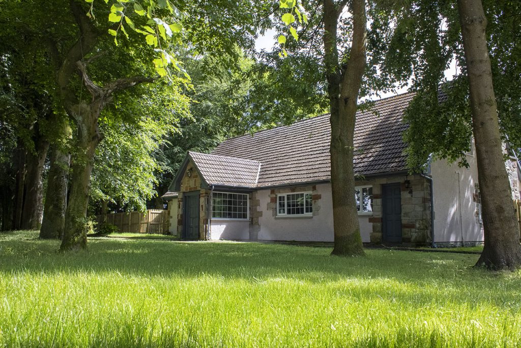 External image of the house with trees all around on a sunny day