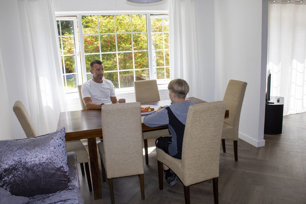 Talking with Sinclair, a young boy chats in the lounge at a table