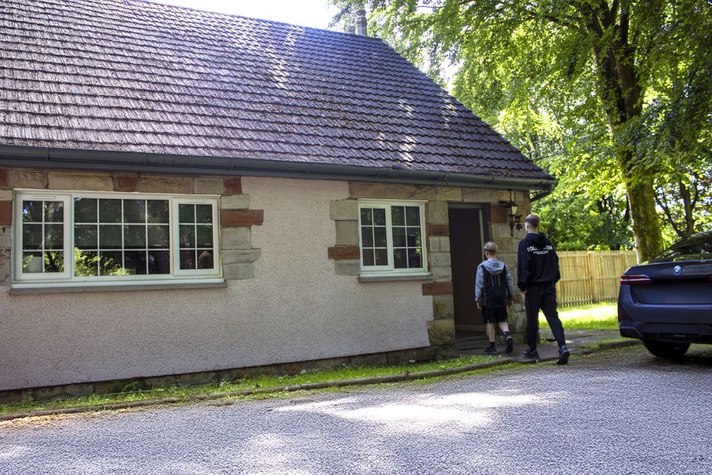 2 young boys entering the house from the driveway